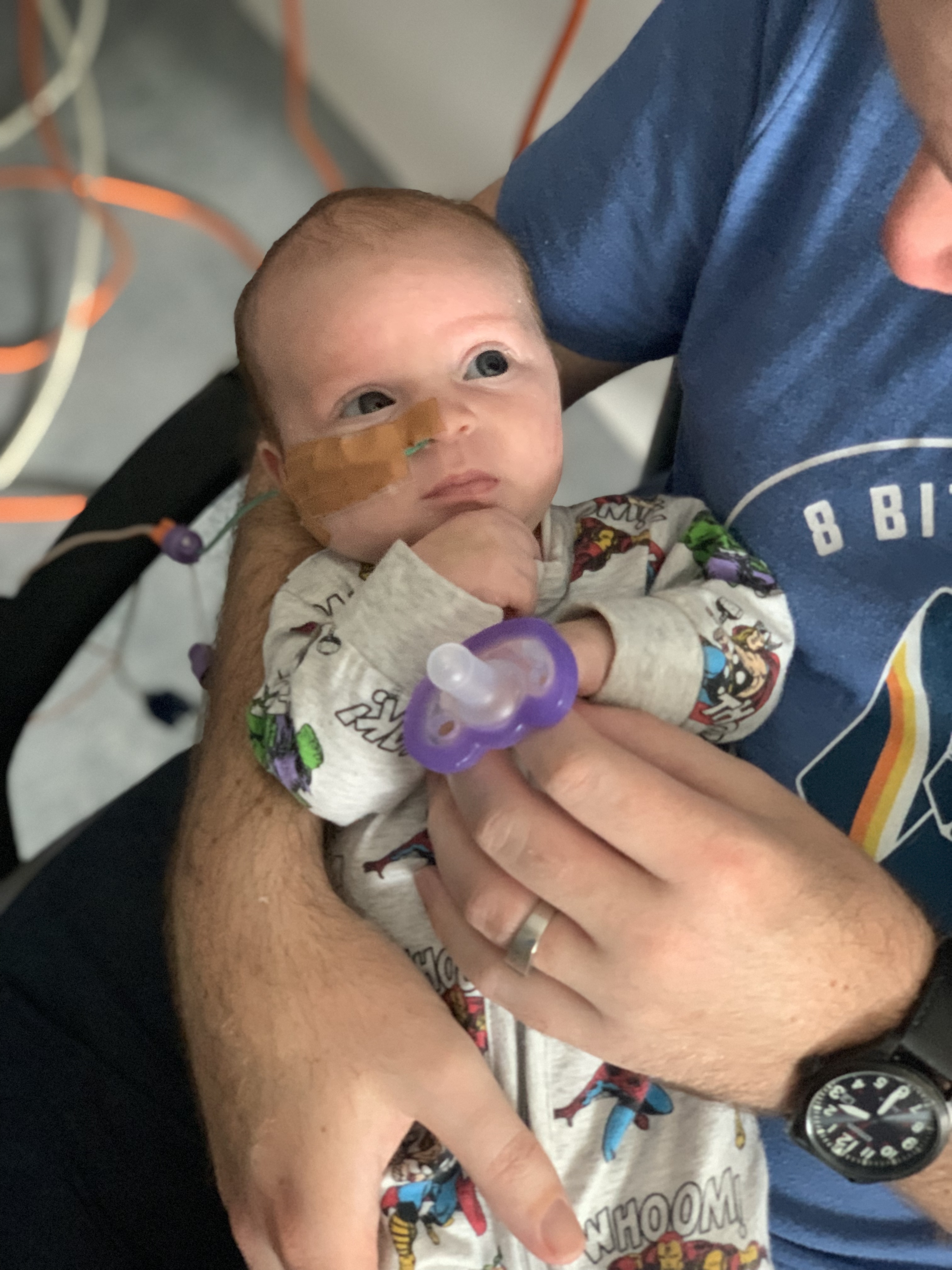 Image of baby in hospital being held by father.