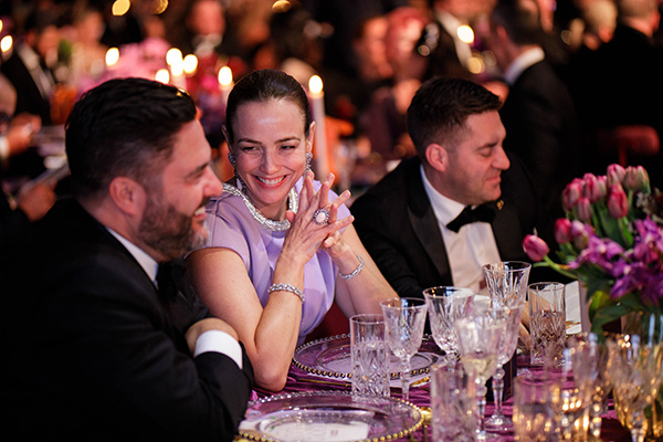 Three guests smiling as they chat while sitting at a dining table at Gold Dinner 2025