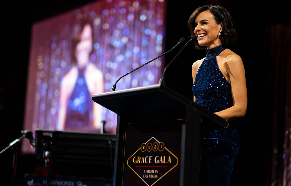 A host standing at the podium speaking at Grace Gala in 2021