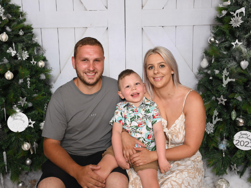 Austin and his parents posing for a Christmas photo