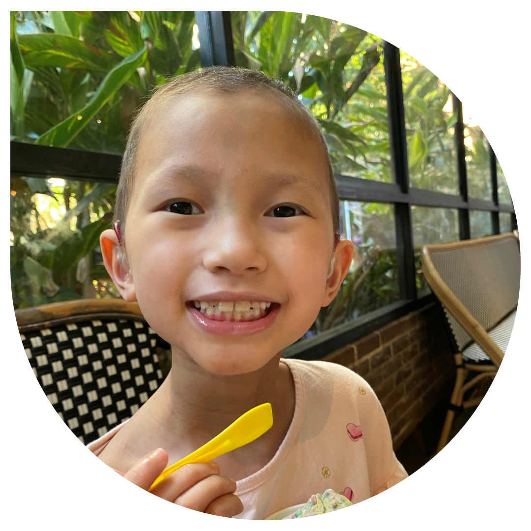 Image of Elise, smiling and eating an icecream from a yellow spoon.