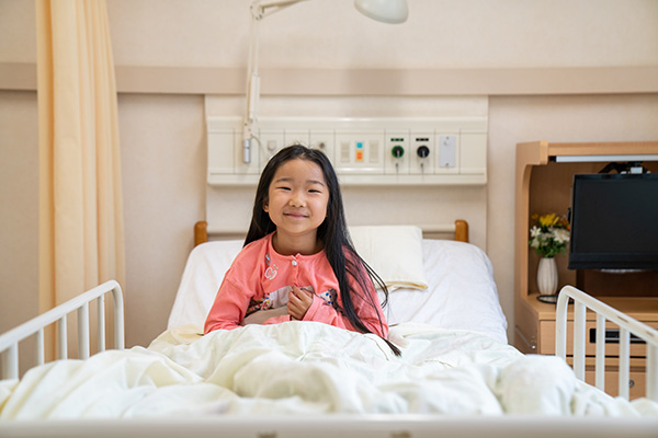 Young girl sitting in a hospital bed with a big grin Young girl sitting in a hospital bed with a big grin
