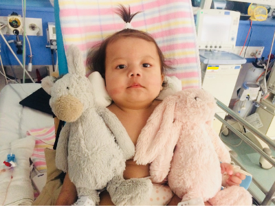 Lucia in hospital with two plush bunny rabbits