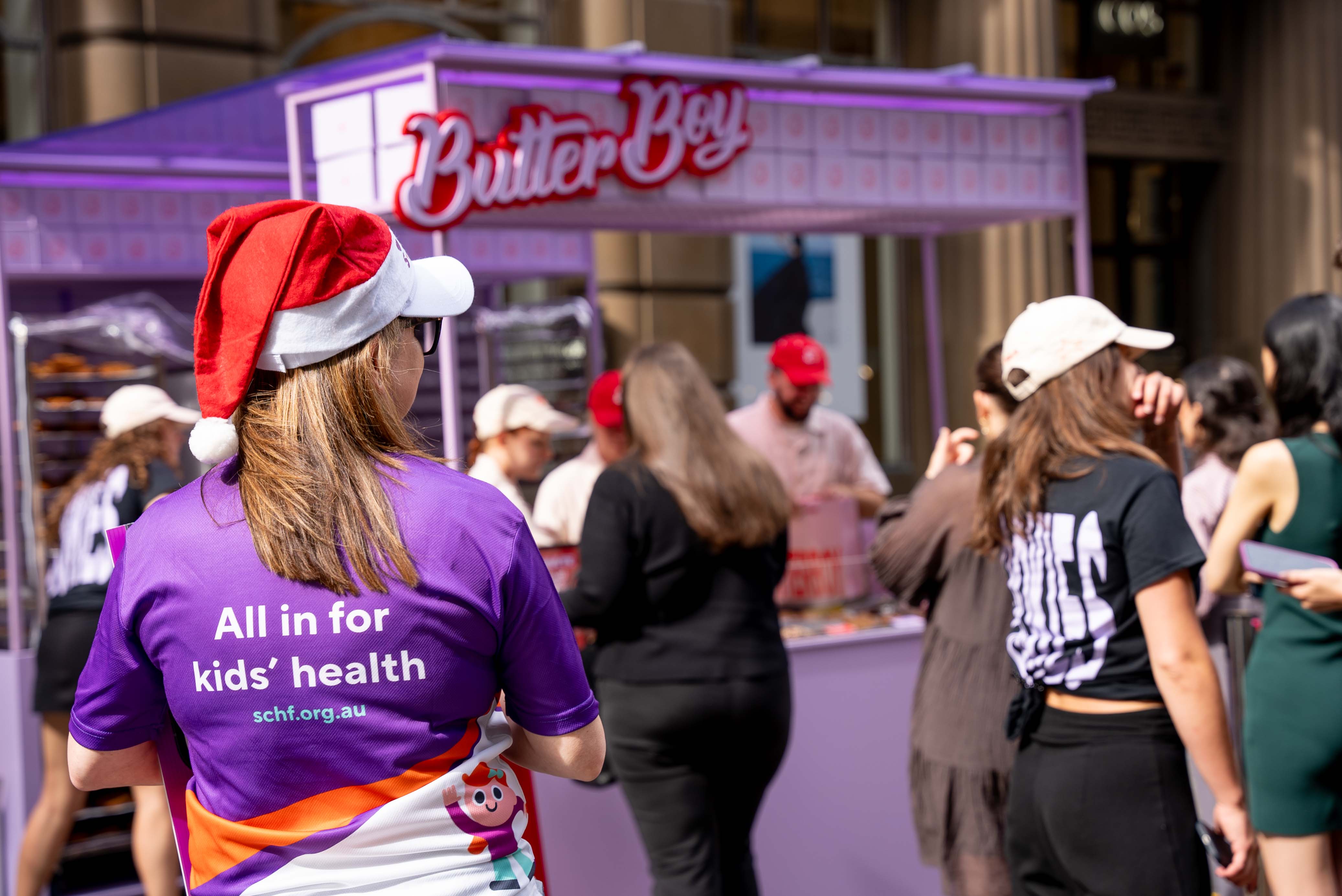 Image of Butter Boy stand with SCHF volunteer standing in front wearing Christmas hat. Image of Butter Boy stand with SCHF volunteer standing in front wearing Christmas hat.