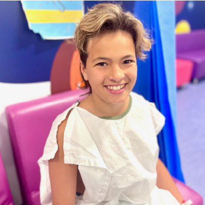 Remy looking happy as he sits on a purple seat in a white hopsital gown. he's wearing a blue medical helmet on his head. Remy looking happy as he sits on a purple seat in a white hopsital gown. he's wearing a blue medical helmet on his head.