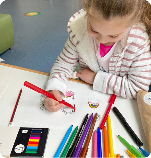 A young girl using a red marker pen