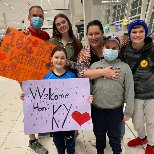 Ky and his family holding up 'welcome home' signs at the hospital