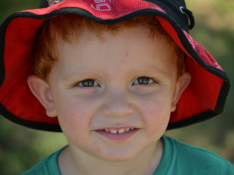 Blake with a cute grin wearing a bright red bucket hat