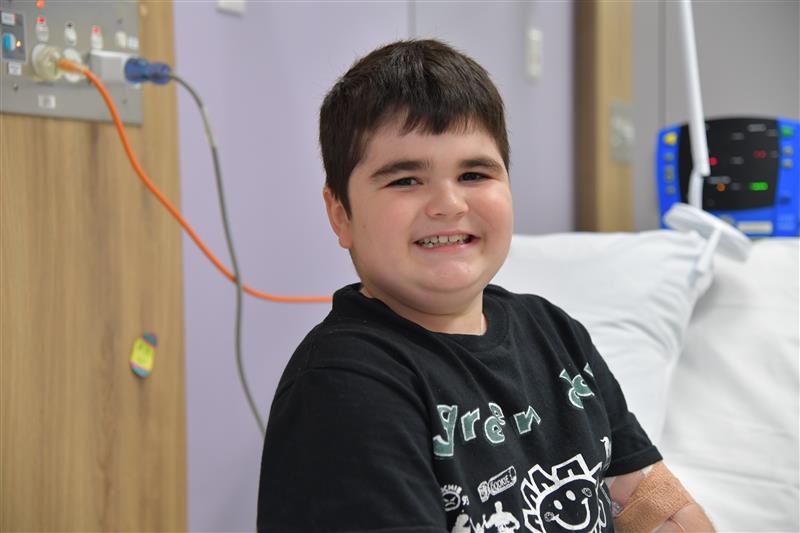 Image of child sitting on hospital bed in clinical room.