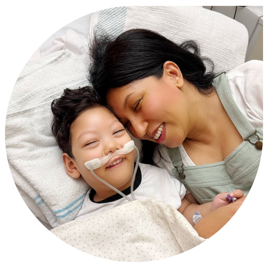 Image of boy laying in hospital bed with mum.