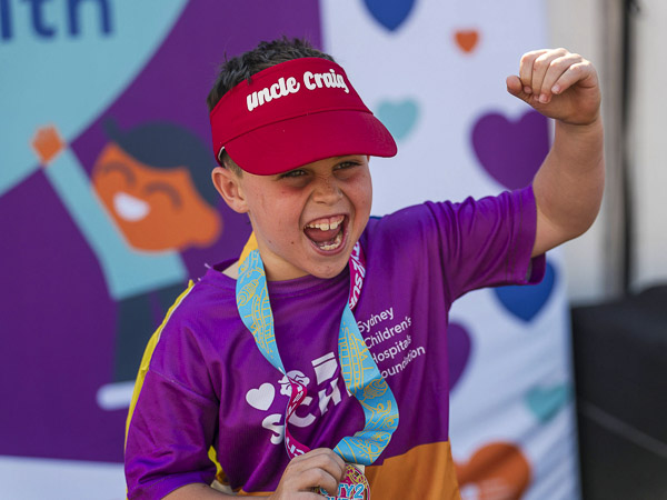 A boy cheering with his fist in the air after finishing the Walk for Kids with Cancer