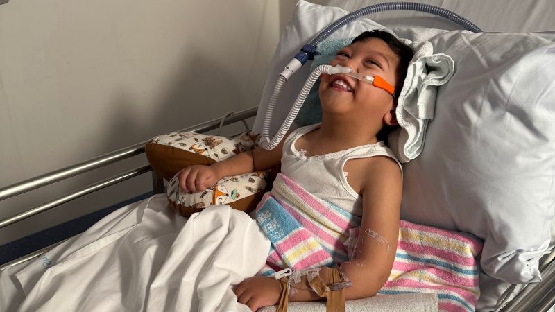 Lucas in a hospital bed, with ventilator support