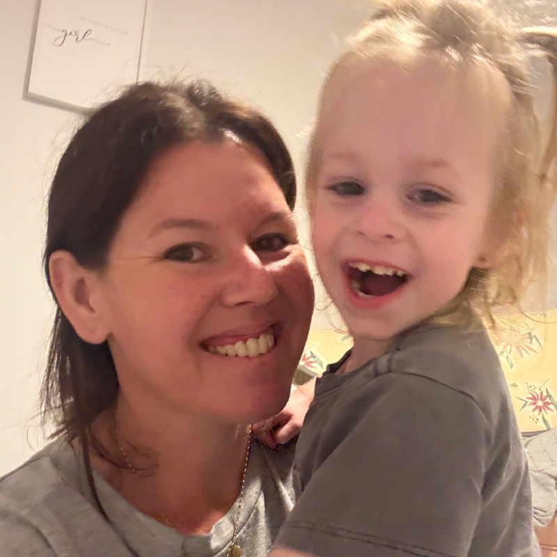 Tilly at two years old with her mum. They are hugging and smiling.