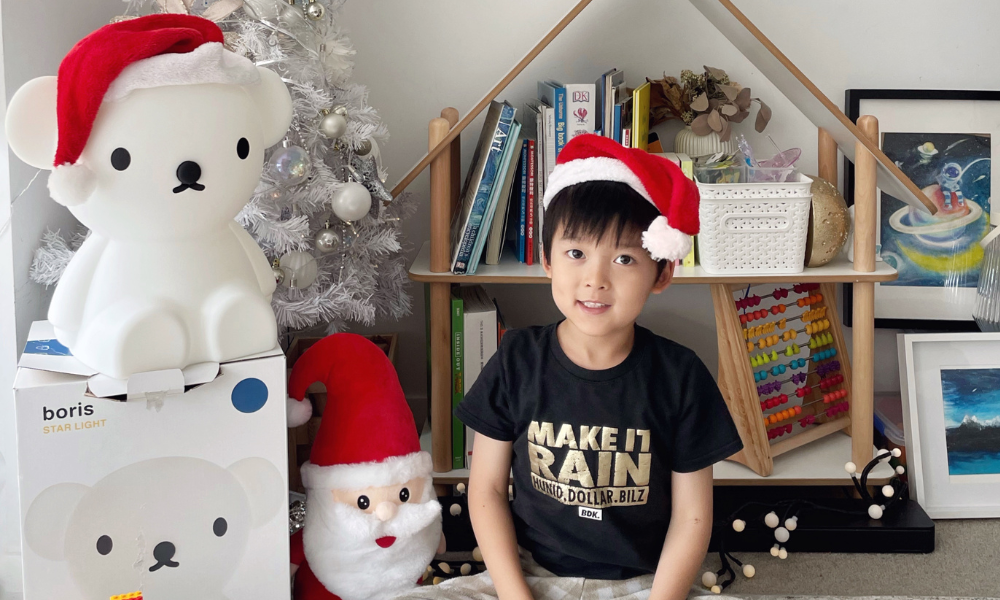 James wearing a Santa hat sitting next to a Christmas tree at home