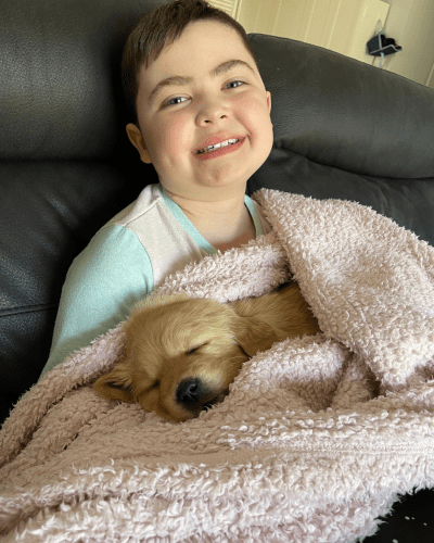 Cooper laying on the lounge with his puppy curled up in a blanket asleep on his lap