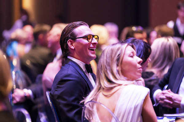 Two attendees smiling while sitting at their table at Grace Gala 2025