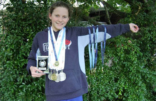 Jasmine holding her swimming medals