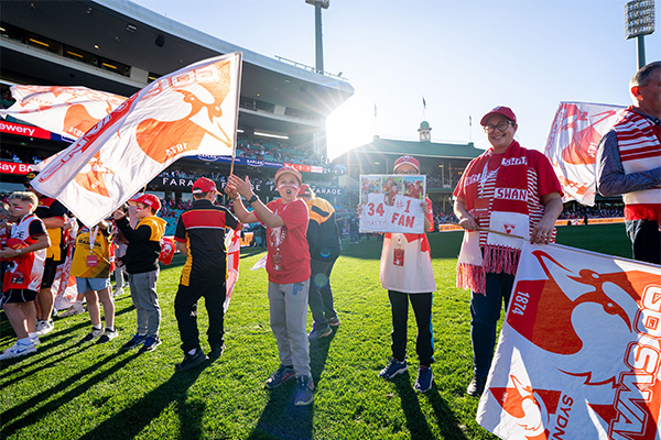 Sydney Swans supporters holding signs and flags on the field