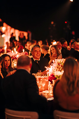Gold dinner attendees sitting around dining tables chatting and enjoying the night.