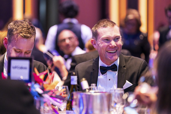 A man sitting at a table smiling widely