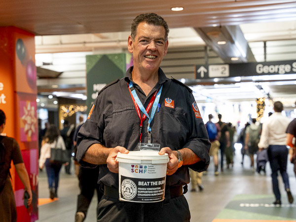 A NSW firefighter collecting donations for SCHF at a train station