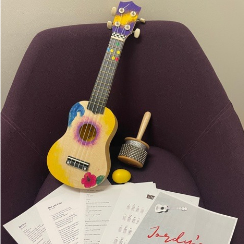 A Ukulele and two different shakers on a chair