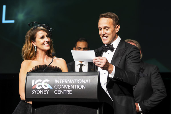 Natalie Barr and Matt Shirvington announcing to the audience on stage at Emerald Ball 2025