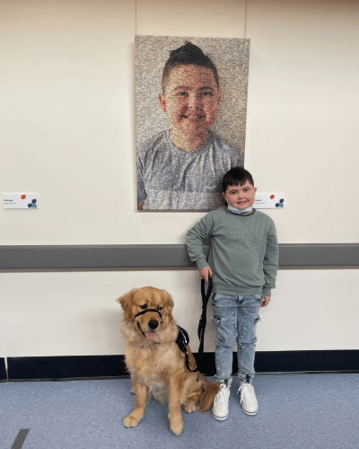 Cooper and his dog standing in front of his A Little Piece of Me artwork hung in the halls at The Children's Hospital at Westmead