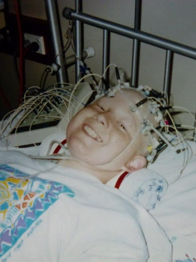 Image of patient smiling on hospital bed with medical equipment attached to head. Image of patient smiling on hospital bed with medical equipment attached to head.