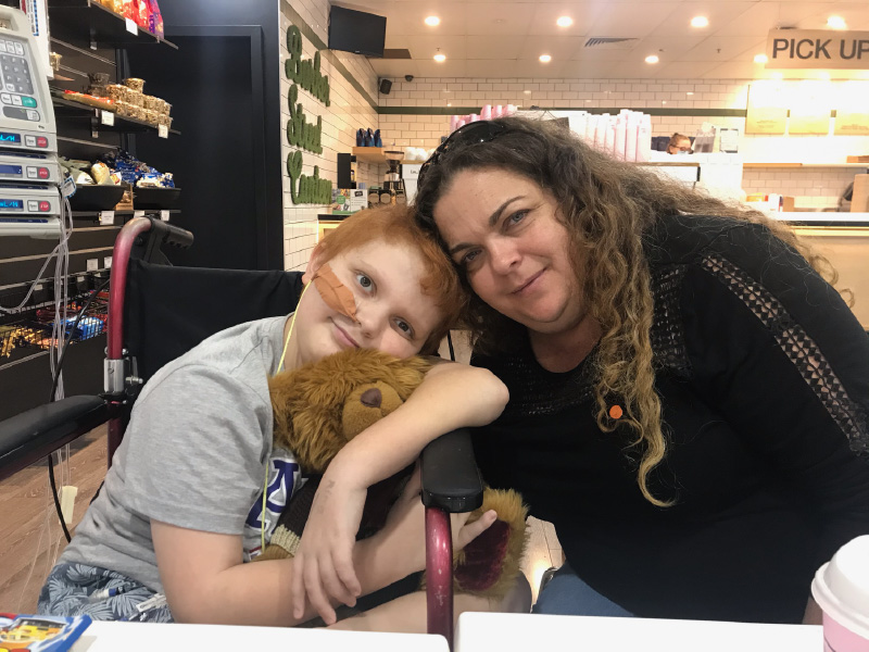 Blake and his aunt in hospital. They're leaning on each other, heads touching. Blake holds a fluffy brown teddy bear. Blake and his aunt in hospital. They're leaning on each other, heads touching. Blake holds a fluffy brown teddy bear.