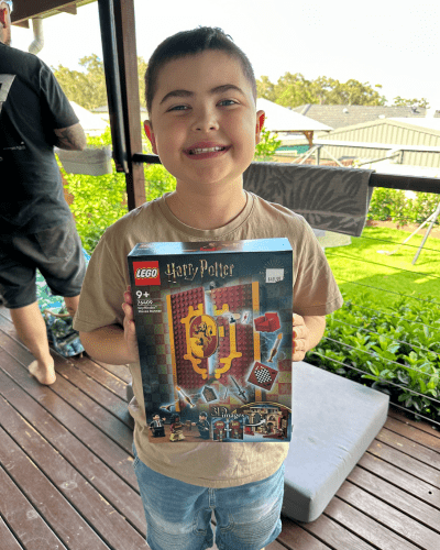 Cooper standing on his balcony proudly holding a LEGO Harry Potter box