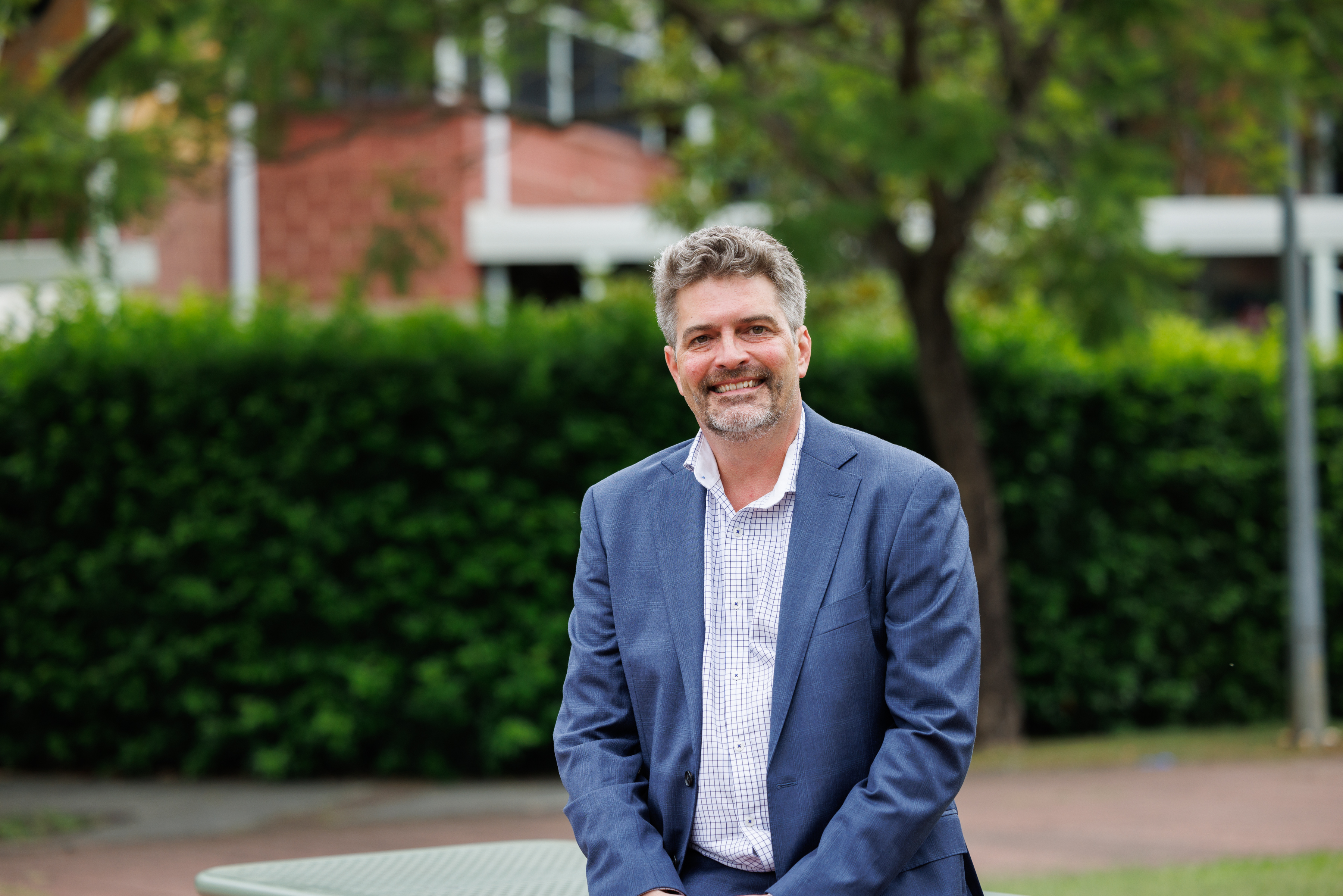 Image of Dr Steven Keogh sitting outside leaning against table and smiling.