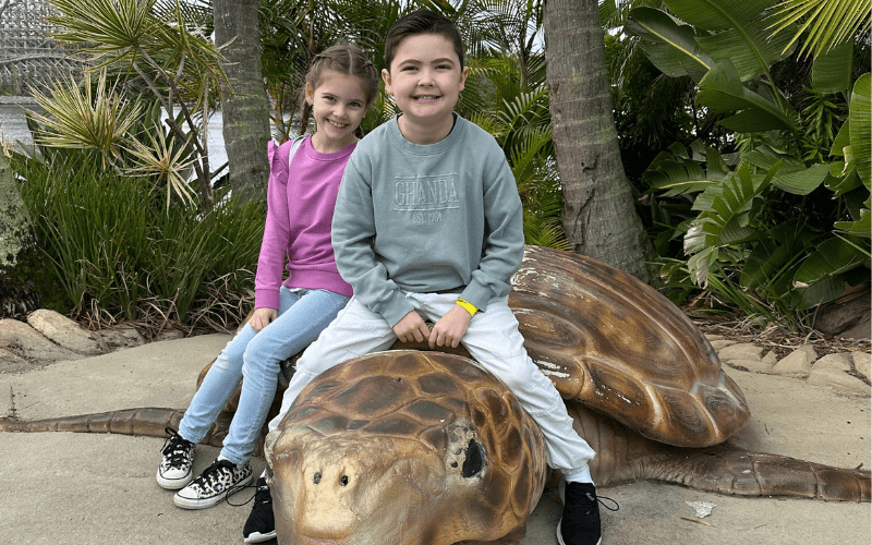 Cooper and his sister sitting on a giant turtle sculpture looking very happy