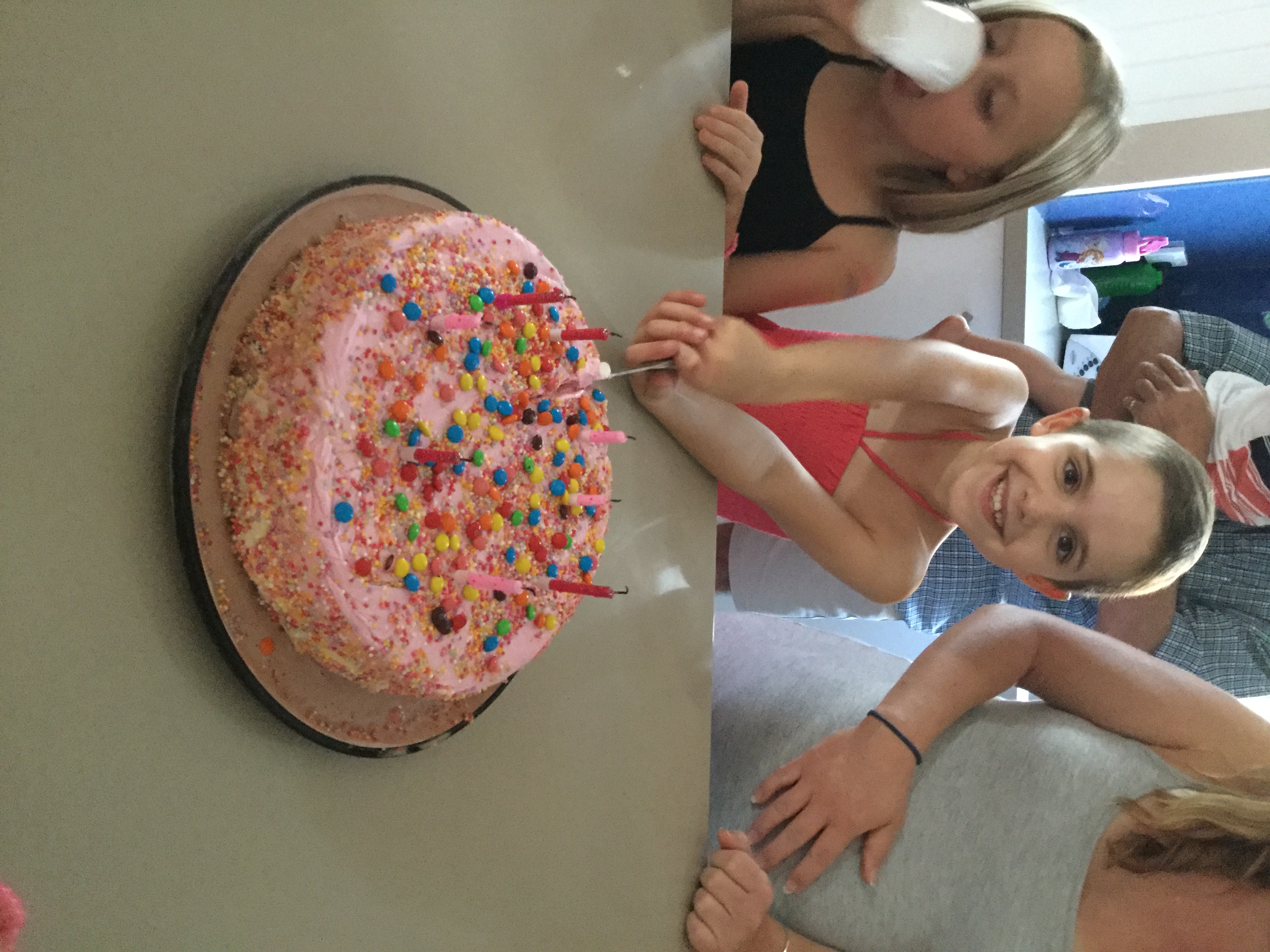 Kyla with a birthday cake that has pink icing and sprinkles
