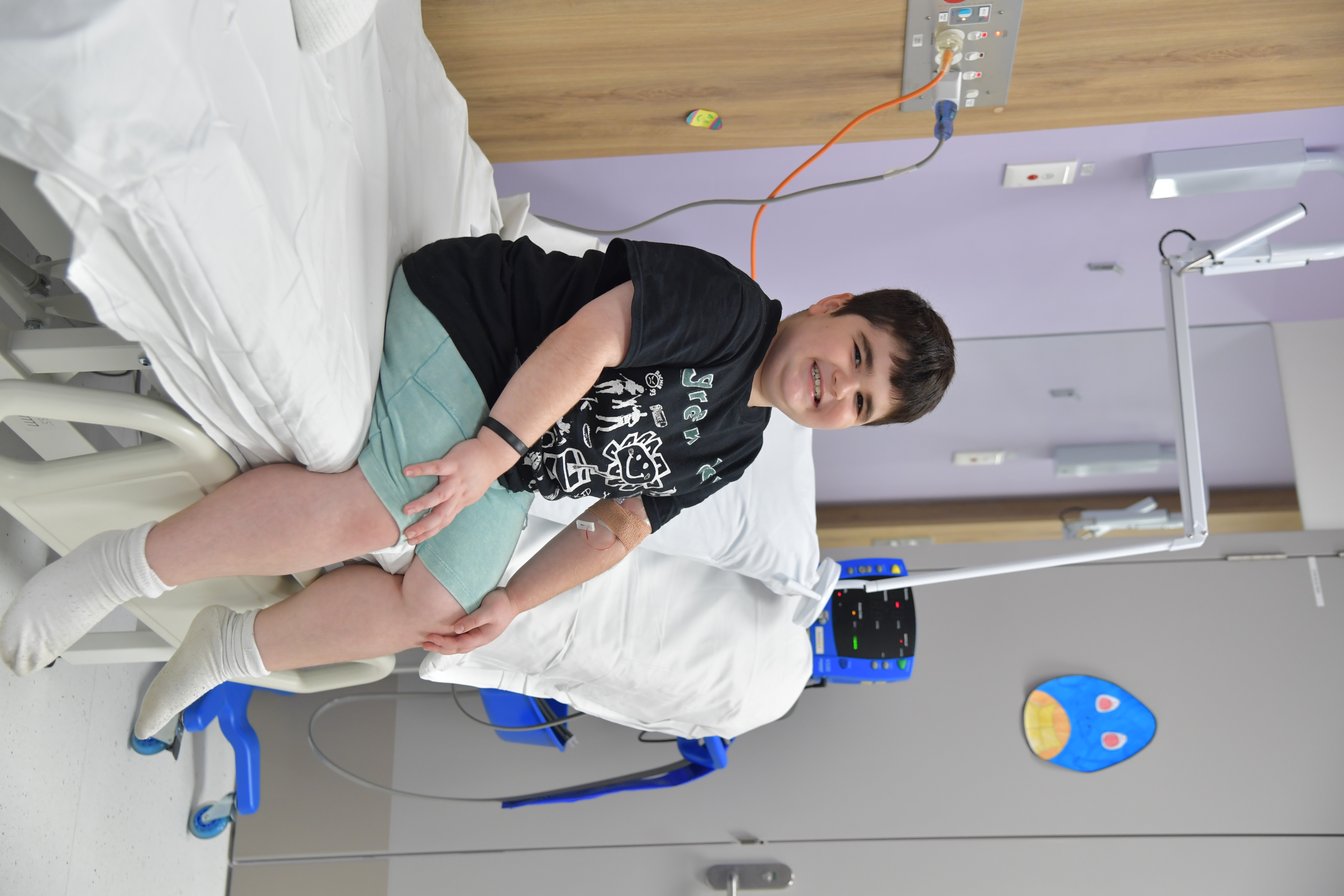 Image of patient sitting on hospital bed in clinical room. Image of patient sitting on hospital bed in clinical room.