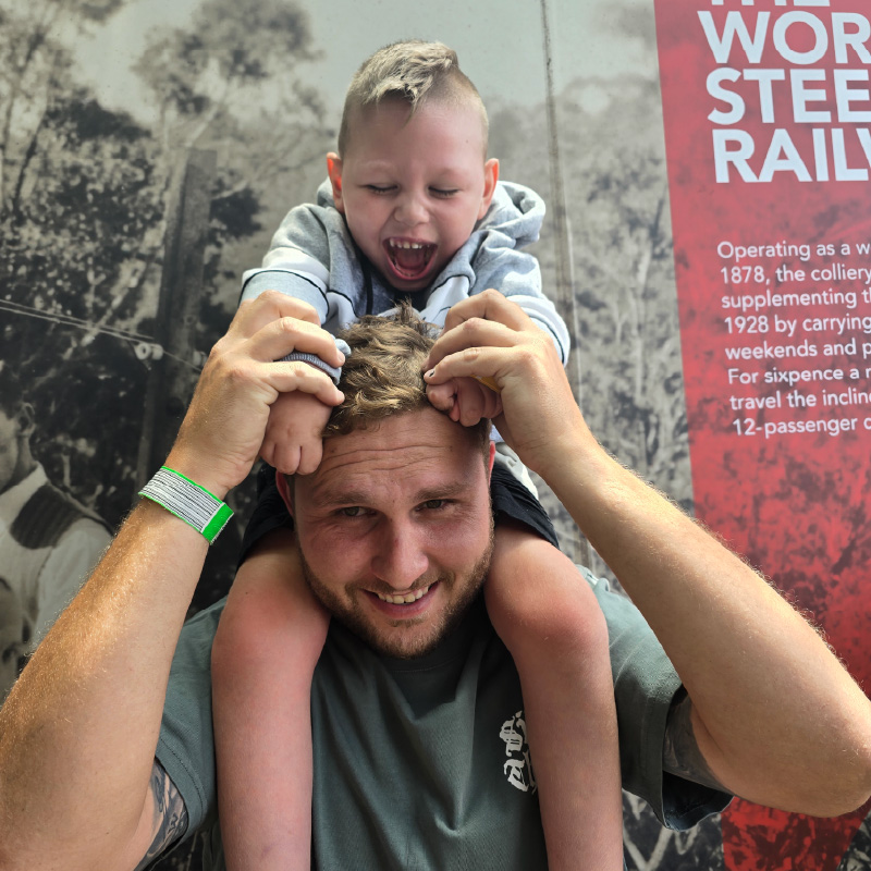 Austin sitting on his dad's shoulders with a huge smile on his face