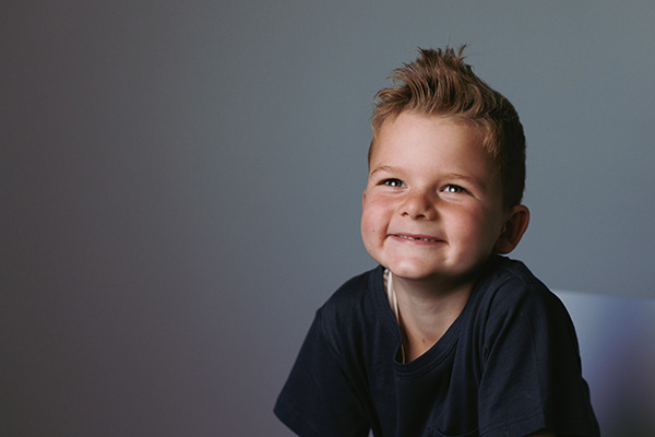 Young boy sitting on a chair smiling from ear to ear