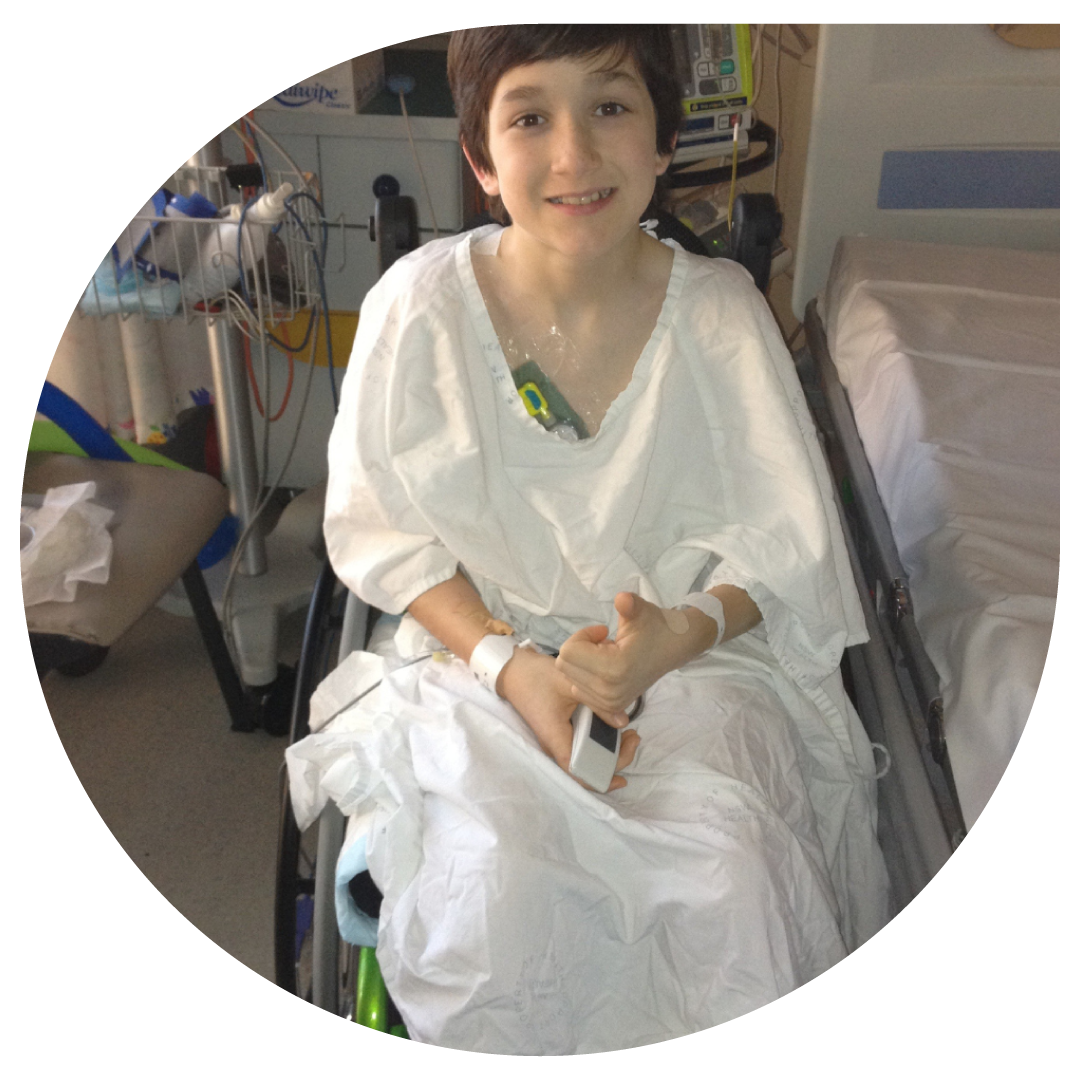 Image of child sitting in wheelchair beside hospital bed.