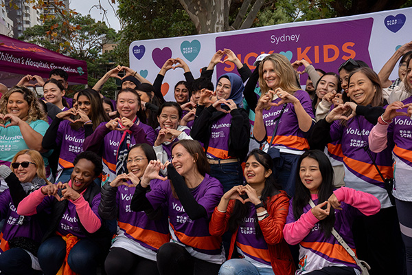 A group of volunteers at Sydney Sick Kids Day making heart gestures with their hands
