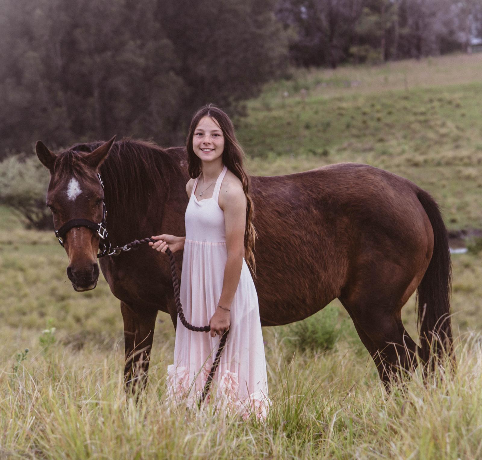 Bridgette standing with a beautiful horse in a grassy field