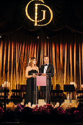 Natalie Barr and Matt Shirvington announcing to the audience on stage at Gold Dinner 2025
