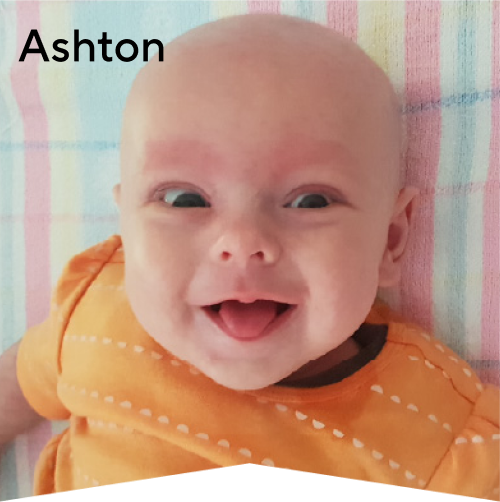 Baby Ashton laying on a blanket poking his tongue out cheekily