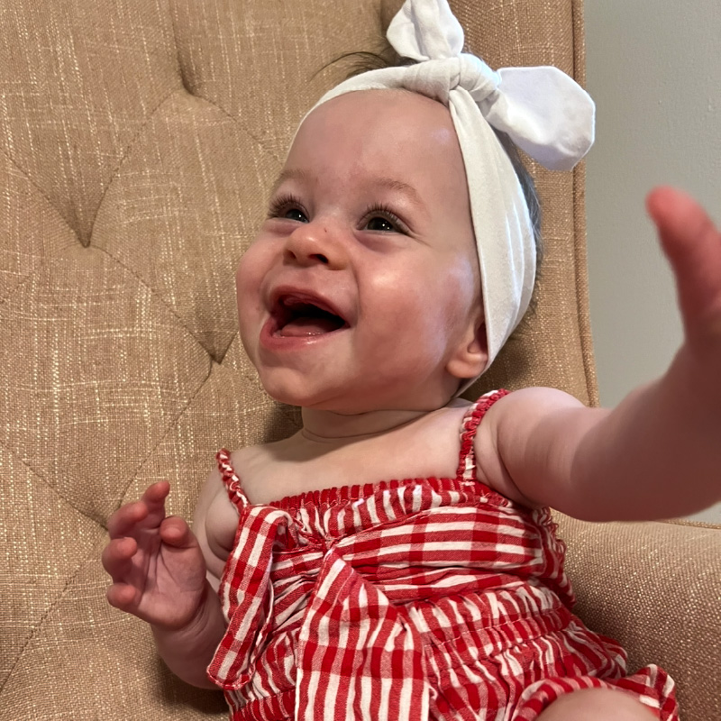 matilda sitting on a chair wearing a red outfit, smiling from ear to ear