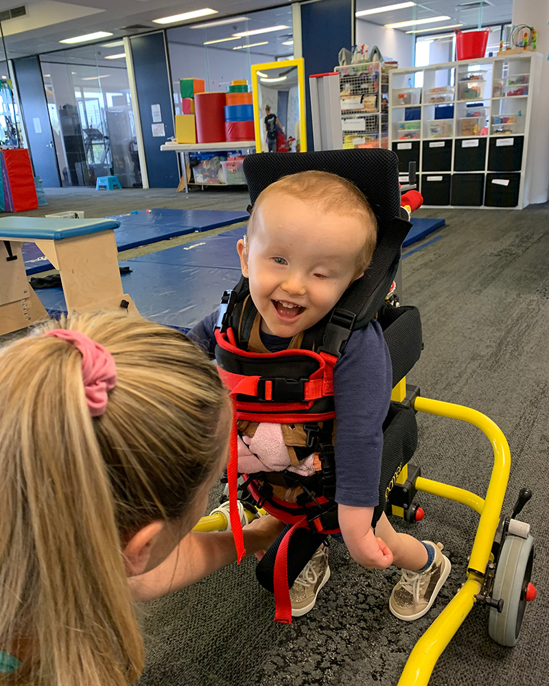 Archie taking steps in his specialized walker