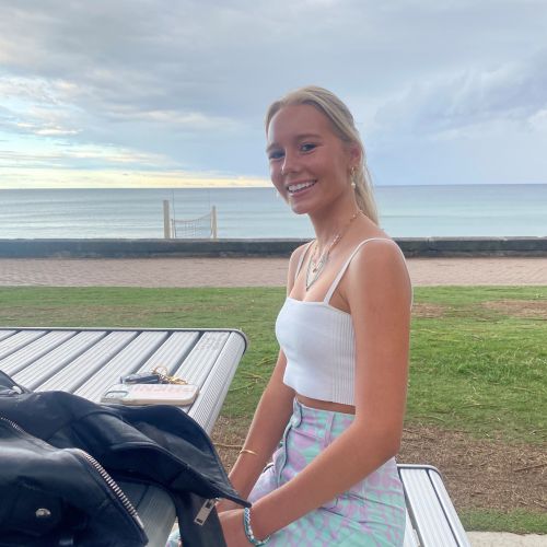 Phoebe sitting at a table near a beach